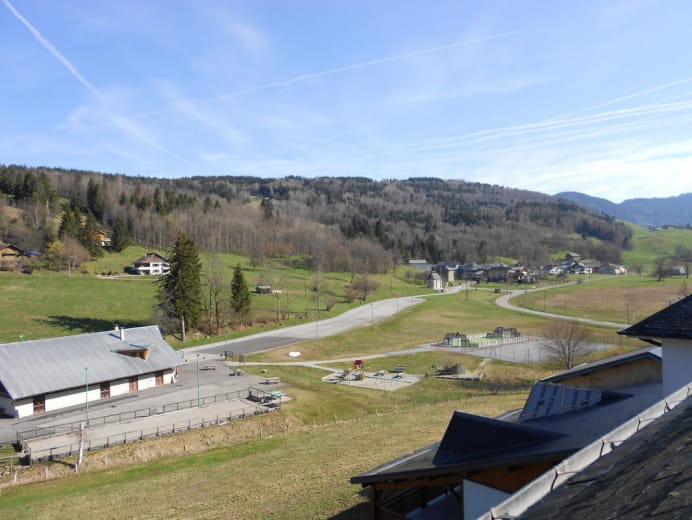 Vue du gîte sur l'espace jeux (balançoires, ensemble mur escalade - toboggan, terrain de tennis, terrain de jeux, table de ping pong)